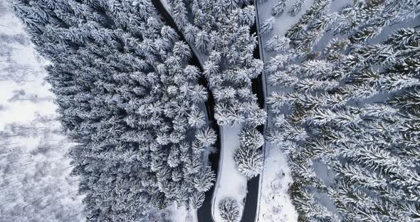 Overhead Aerial Top View Over Hairpin Bend Turn Road in Mountain Snow Covered Winter Forest