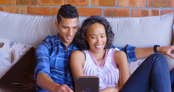 Couple using digital tablet on sofa 4k