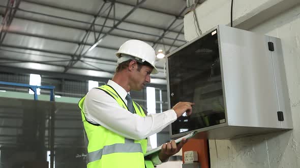 Mature Man Inspecting Equipment in Factory