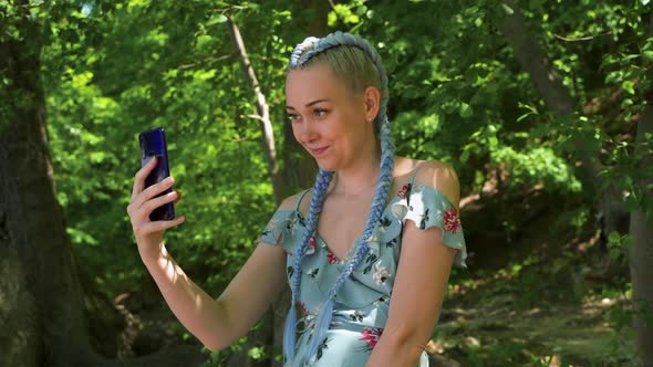 Young creative hipster woman using mobile phone to chat online or take selfie