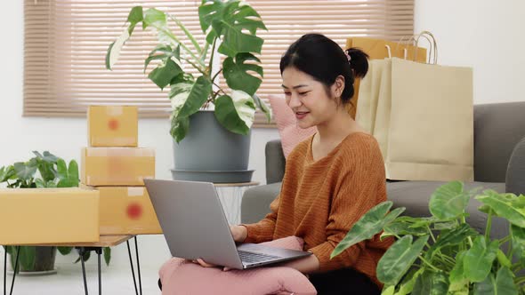 Happy young Asian woman enjoy to shopping from online shopping platform by laptop computer.