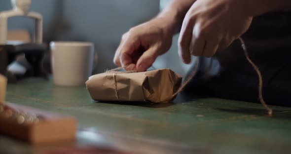 Male Artisan Wrapping Parcel on Table