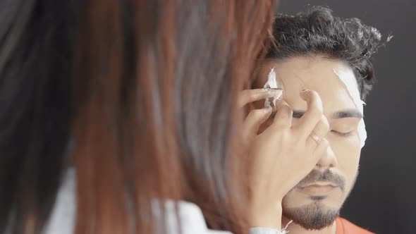 Make up artist putting white prosthetic insert on man's face