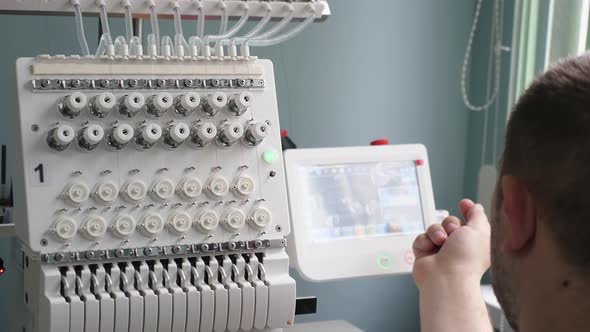 Worker Is Programming a Sewing Machine with a CNC Using a Tablet Computer. The Operator Sets Up the