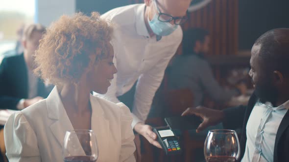 Happy Couple Using Mobile Phone and Making Contactless Payment in Restaurant