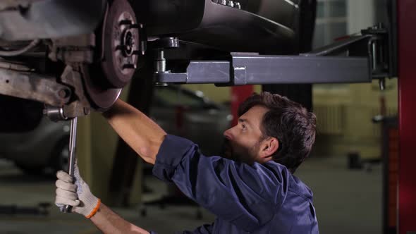 Focused Repairman Using Tool To Check Car Chassis