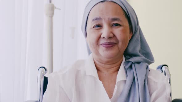 An elderly woman with cancer in a wheelchair during hospitalization.