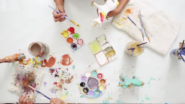 Step by step. Little girls painting paper mache unicorn with acrylic paint.