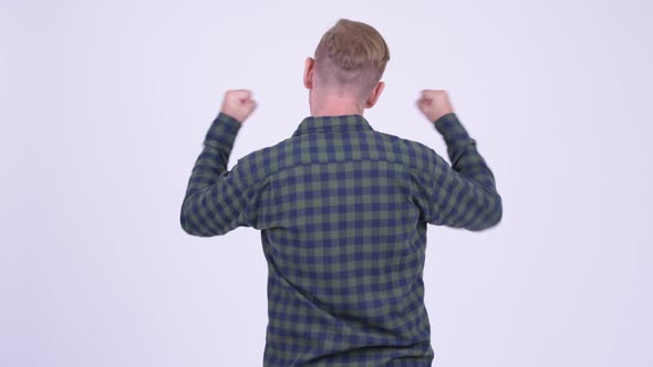 Rear View of Blonde Hipster Man Excited with Arms Raised