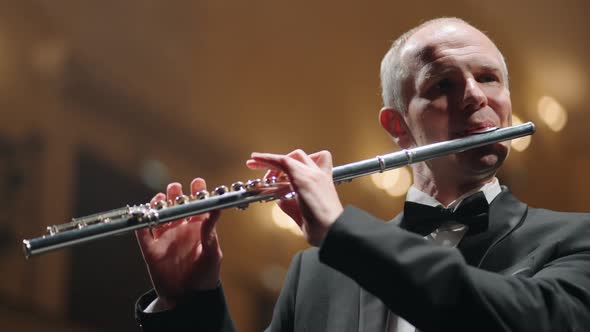 Grey Haired Flutist is Playing Music in Philharmonic Hall Rehearsal or Concert of Symphonic