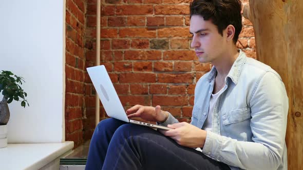 Thumbs Down By Man Working on Laptop Loft Office