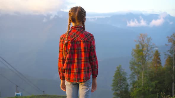 Beautiful Happy Little Girl in Mountains in the Background of Fog