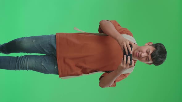 Asian Boy Student Playing Game On Mobile Phone While Walking To School On Green Screen