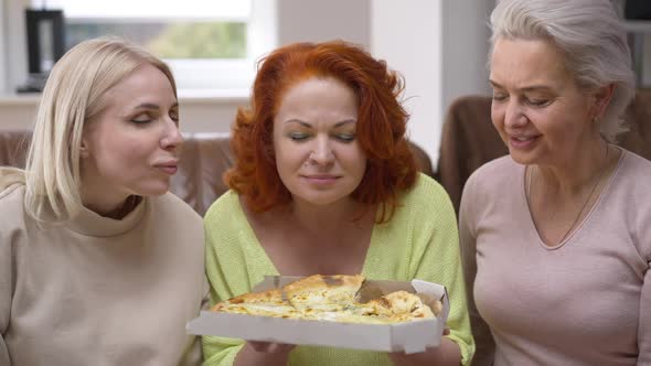 Front View Three Caucasian Beautiful Women Smelling Tasty Pizza Talking Sitting in Living Room at