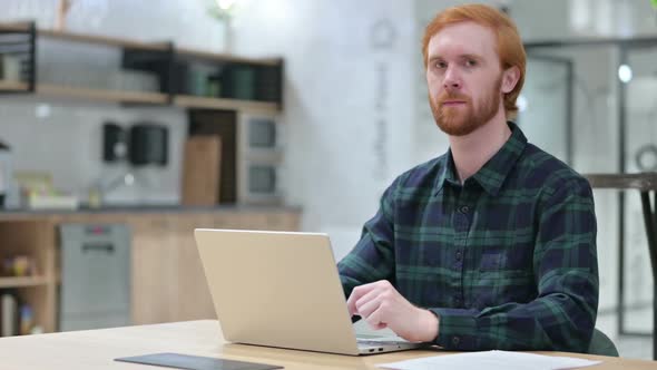 Beard Redhead Man with Laptop Looking at the Camera