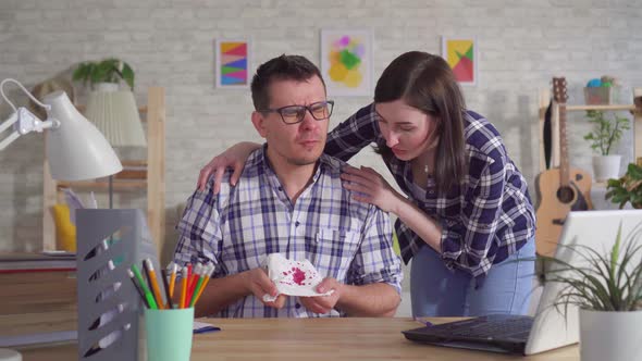 Young Man in Glasses Sitting at Laptop Coughs with Blood His Wife Supports