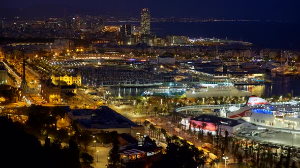 Cars Going the Streets of Night Barcelona, Spain. Ships Are Moored By the Shore. The City Is Shining