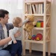 Baby boy with father taking toys from bookshelf - VideoHive Item for Sale
