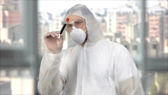 Medical Worker in White Protective Clothing and Mask Holding Test Tube with Blood