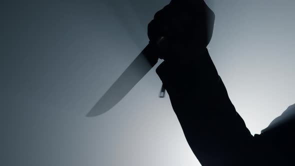 Silhouette Criminal Hand Attacking with Knife in Darkness