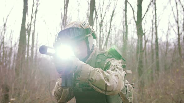 Armed Young Man in a Zone of Armed Conflict in Uniform Targeting with Assault Rifle Walking in