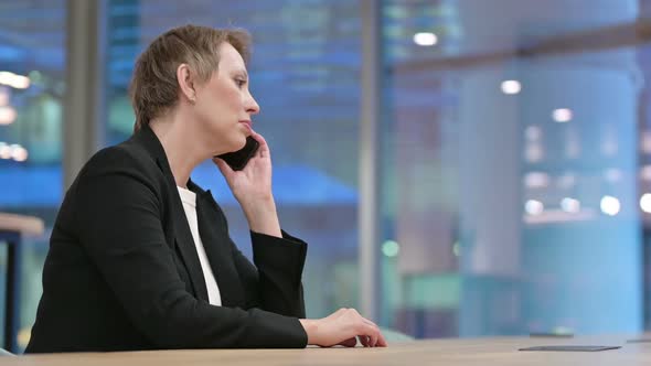 Old Businesswoman Talking on Smartphone in Office