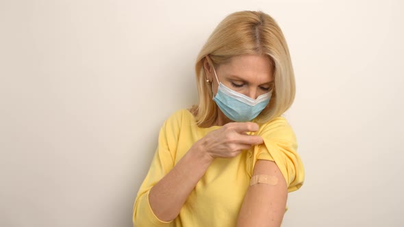 Portrait of Caucasian Senior Woman Wearing Medical Mask Showing Her Arm with Band