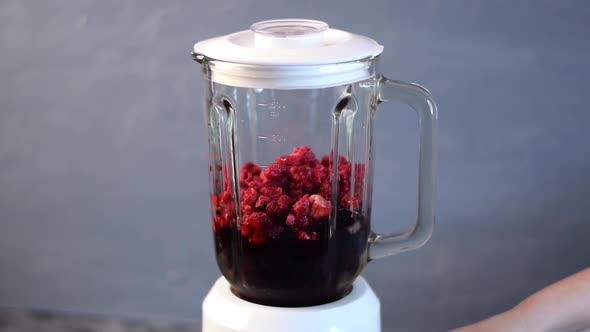 Frozen raspberry and blueberry are blended in electric blender