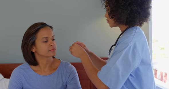 Mixed race female doctor inserting a hearing aid machine on womans ear at home 4k