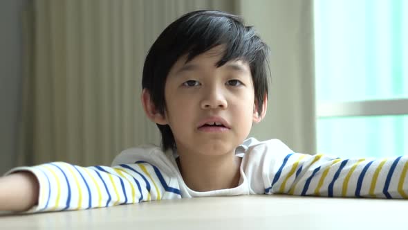 Unhappy Asian Child Resting Chins On Hands On Wood Table