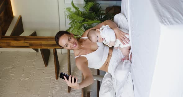 A Young Mother with Her Newborn Daughter During an Online Video Chat with Her Father