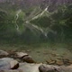 Tilt Up Shot Of Rocks In A Clear Lake Against Mountains In Morskie Oko - VideoHive Item for Sale