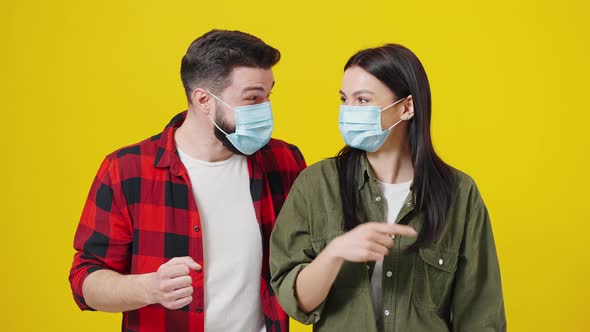 Couple in Protective Masks Dancing on a Yellow Background