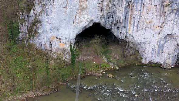 Aerial View of a Big Cave Entrance and Wild Mountain River