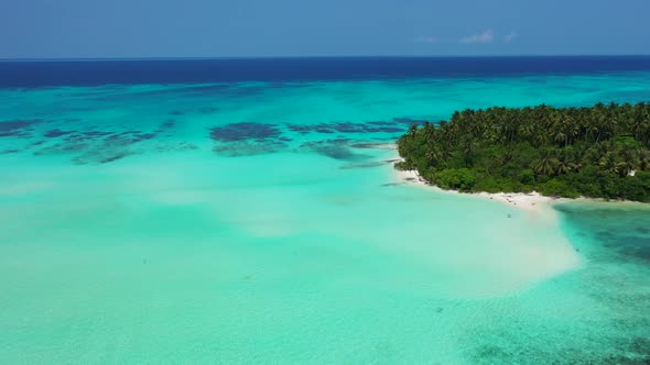 Aerial drone shot sky of idyllic resort beach break by blue green lagoon and bright sand background 