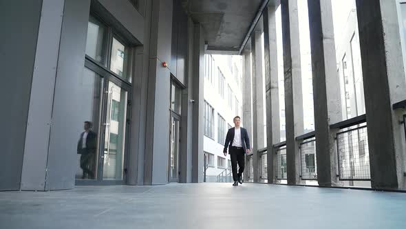 young successful asian businessman walking along the corridor of a modern office building 