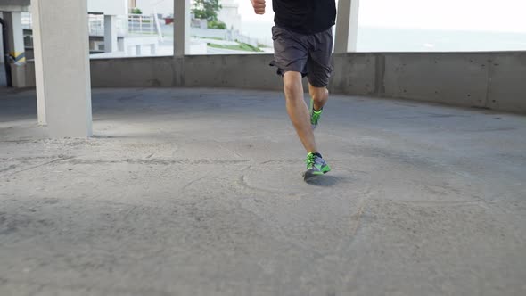 Unrecognizable Athlete Runs Around By Levels of an Empty Parking Garage Front View