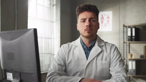 Portrait of Serious Young Man Looking at Camera While Sitting in Medical Office