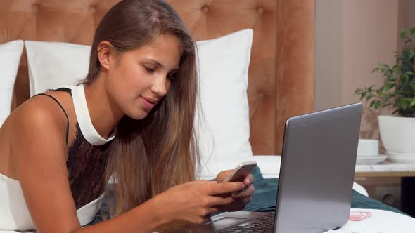 Happy Beautiful Woman Using Smartphone at the Hotel Room