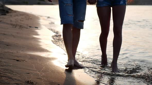 Happy Couple Holding Hands Strolling Along the Shore, Walking on the Sand Barefoot on the Sea Waves