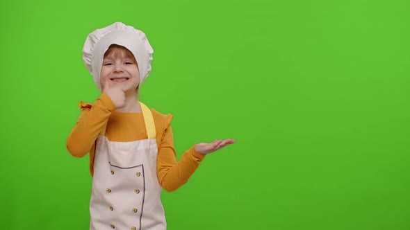 Child Girl Dressed Cook Chef in Apron Pointing at Right on Blank Space on Chroma Key Background