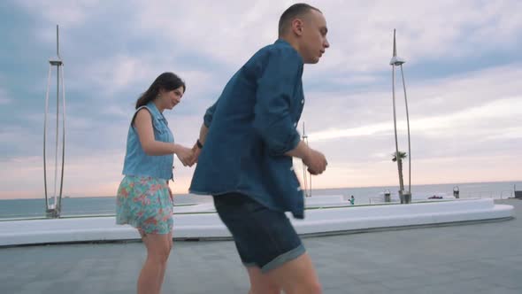 Beautiful Sweet Couple Riding on Roller Skates Quads Holding Hands Near the Sea Slow Motion