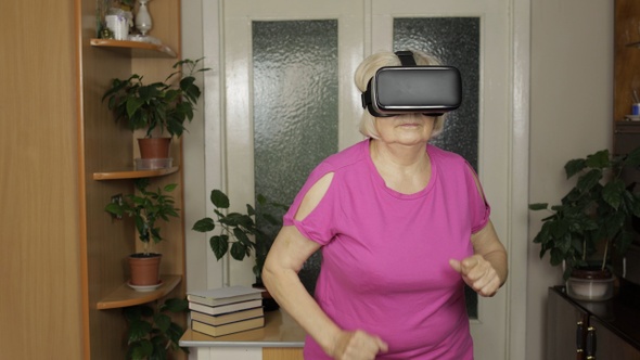 Senior Grandmother in Virtual Headset Glasses Watching 3D Video in VR Helmet and Running at Home