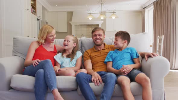 Portrait of happy caucasian parents, son and daughter sitting at home on sofa
