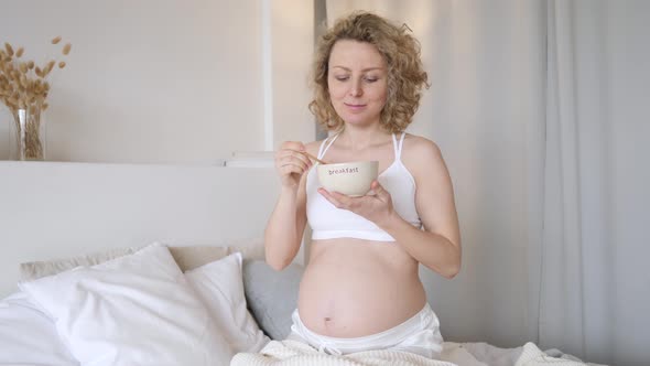 Pregnant Woman Eating Her Meal In Bed