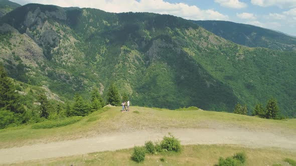 Adventurous Couple Sitting at Mountain Edge