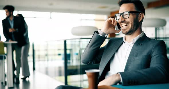 Pensive Young Businessman in Cafe Using Phone