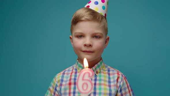 Kid in Birthday Hat Blowing Out Number 6 Candle in Slow Motion