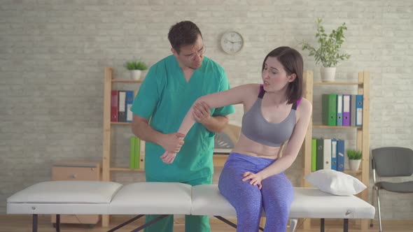 Chiropractor Osteopath Examines the Sick Hand of a Young Woman Athlete
