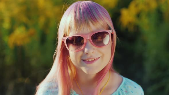 Portrait of a Cheerful Child in Pink Sunglasses with Pink Hair